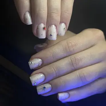 Manicura en blanco perlado con destellos y gemas